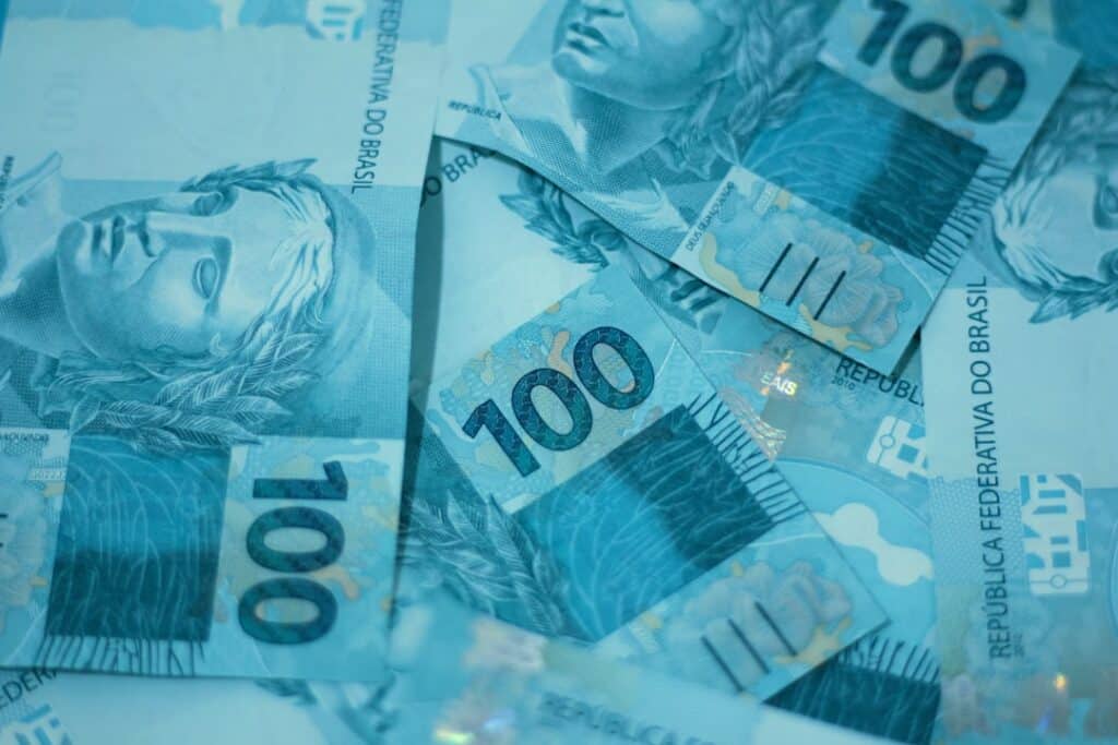 Notas de cem reais brasileiras em destaque na imagem.