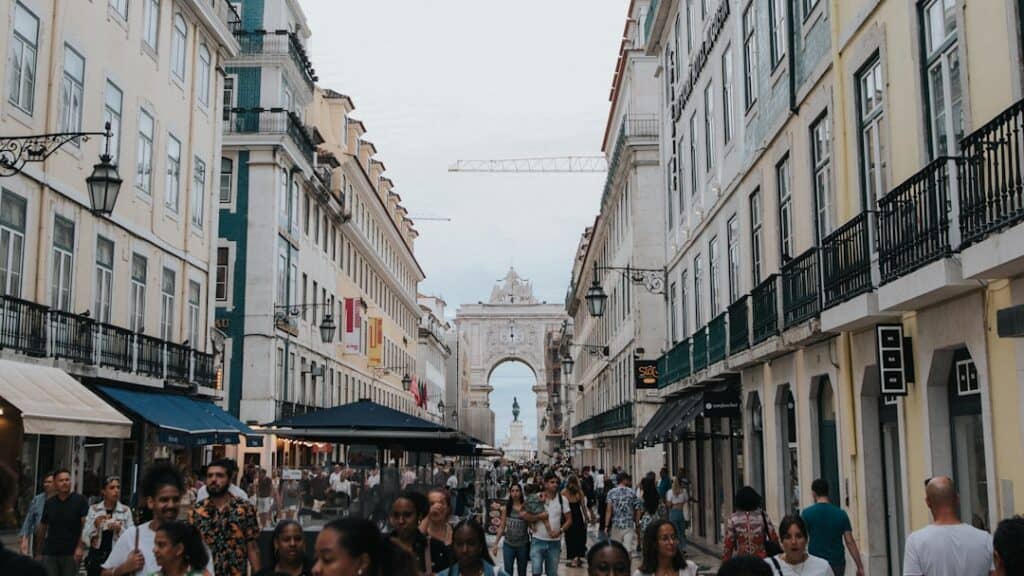 Rua movimentada em Lisboa com arco do triunfo ao fundo.