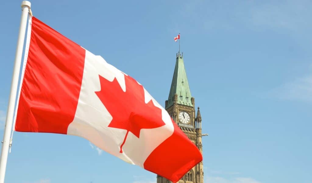 Bandeira do Canadá com o Parlamento de Ottawa ao fundo.